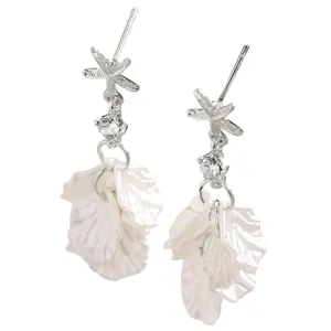 Close-up detail of silver starfish earrings with clear rhinestones and white shell petals