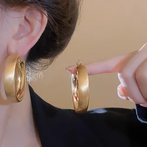 Detail view of large gold brushed hoop earrings with a minimalist and elegant design