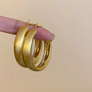 Detail view of matte gold hoop earrings with brushed finish and minimalist design.