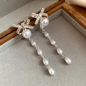 Detailansicht von silbernen Schleifenohrringen mit eleganten hängenden Tropfenperlen