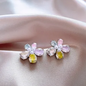 Vista dettagliata di eleganti orecchini a fiore con zirconi colorati e perle centrali