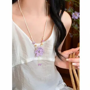 Close-up of a handmade purple woven flower necklace worn by a model in vacation style