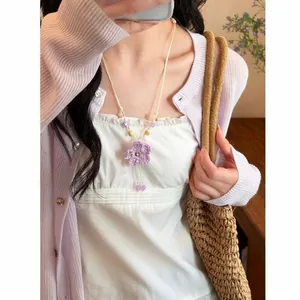 Detail view of a handmade purple woven flower necklace with delicate bead accents.