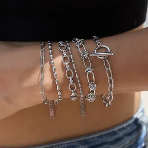 Gros plan de bracelets en acier inoxydable argenté empilables aux textures variées.