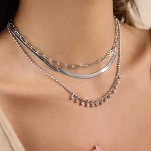 Gros plan d'un ensemble de colliers superposés en acier inoxydable argenté avec cristaux
