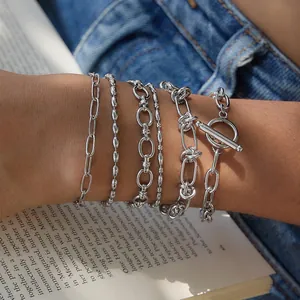 Vue détaillée de plusieurs bracelets en acier inoxydable argenté superposés sur un poignet