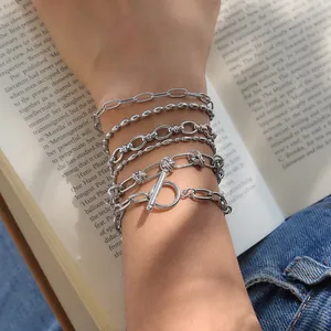 Gros plan de bracelets superposés en acier inoxydable argenté sur fond de livre ouvert.