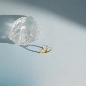 Detailed view of a gold square sugar zircon ring on a light blue background with quartz.