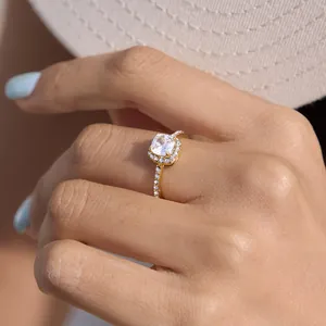 Close-up of gold titanium steel ring with sparkling square zircon halo on finger.