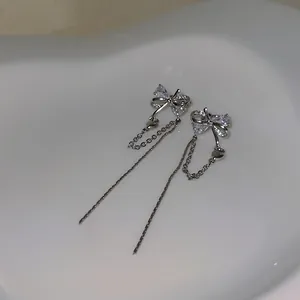 Detailed view of silver butterfly bow ear clips with sparkling crystals and long tassels