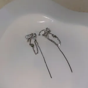 Macro view of silver butterfly tassel ear clips featuring crystals and heart charms