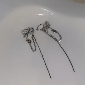 Detailed view of silver bow-shaped tassel ear clips with sparkling cubic zirconia stones