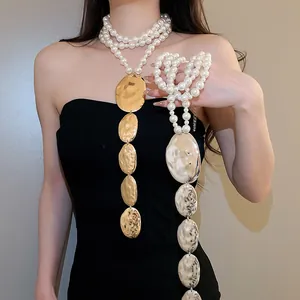 Vue détaillée d'un collier de perles avec des pendentifs ovales martelés dorés et argentés