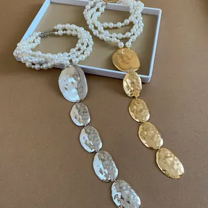 Vue détaillée des colliers dorés et argentés avec pendentifs martelés et perles.