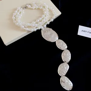 Détail du collier de perles multicouches avec des pendentifs ovales en argent martelé