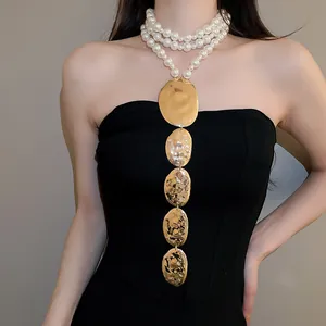 Gros plan détaillé d'un collier de perles multicouches avec des pendentifs ovales dorés.