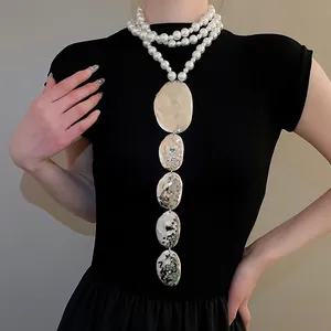 Vue détaillée du collier de perles multicouche avec pendentifs ovales argentés
