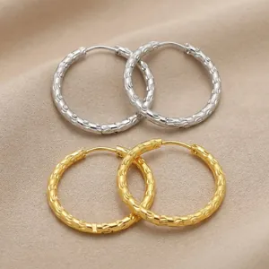 Detailed macro view of textured gold and silver-plated stainless steel hoop earrings