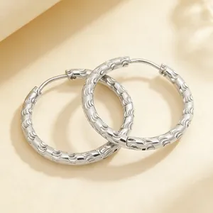Macro view of textured embossed pattern on silver stainless steel hoop earrings