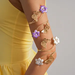 Vista dettagliata di un bracciale da braccio floreale dorato con fiori viola e farfalle.