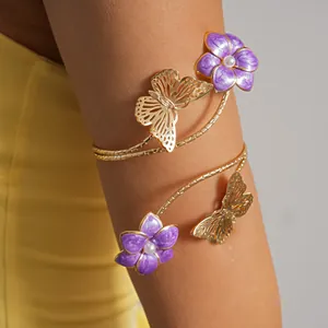 Dettaglio macro di un bracciale da braccio dorato con fiori in smalto viola e farfalla