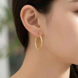 Detailed close-up view of textured 18K gold-plated stainless steel hoop earring on model
