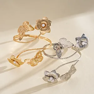 Primo piano di bracciali da braccio in metallo con eleganti motivi a farfalla e fiore di perla.