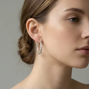 Detailed view of textured silver hoop earrings on a model for a chic, bold look