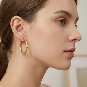 Close-up of textured 18K gold-plated stainless steel hoop earrings worn by model