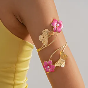 Dettaglio di un bracciale da braccio dorato con fiori in smalto rosa e farfalle
