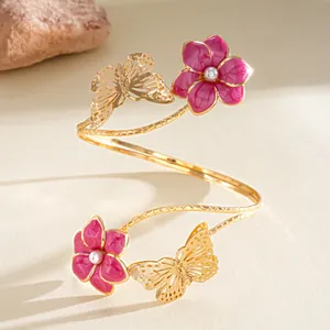 Dettaglio di un bracciale da braccio dorato con fiori in smalto rosa e farfalle di perle