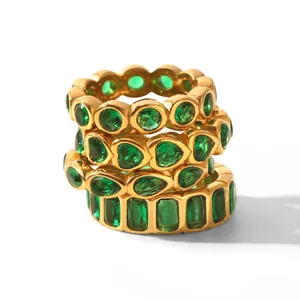 Close-up of stacked gold rings featuring green zirconia in heart, pear, and round cuts