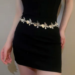 Elegant silver metal flower waist chain necklace accessory worn over a black dress