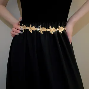 Detailed view of luxury gold metal flower waist chain belt on a black dress.