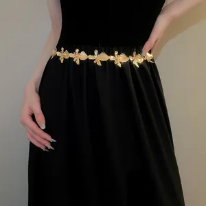 Elegant close-up of a gold metal flower waist chain accessory on a black dress