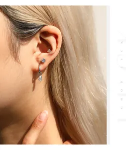 Close-up of sterling silver moissanite heart earring and marquise dangle hoop on ear