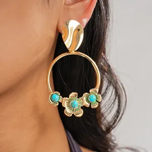 Vue détaillée de créoles dorées rondes avec fleurs turquoise et accents en émail vert.