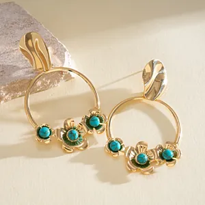 Gros plan détaillé des boucles d'oreilles créoles dorées aux fleurs turquoises