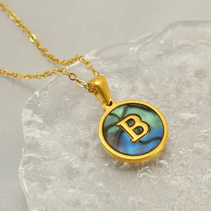 Détail d'un collier en acier inoxydable doré avec un pendentif rond orné de la lettre B