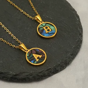 Gros plan de pendentifs lettre dorés A et B avec incrustation de coquillage colorée.