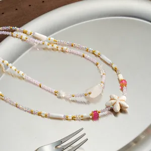 Makroansicht eines Seestern-Anhängers an einer zarten rosa und weißen Muschelperlenkette