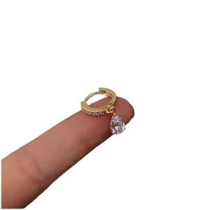 Gold lightning hoop earrings with pear-shaped zircon pendant displayed on finger