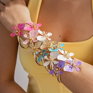 Detail van stijlvolle goudkleurige armringen met levendige ontwerpen van emaille bloemen