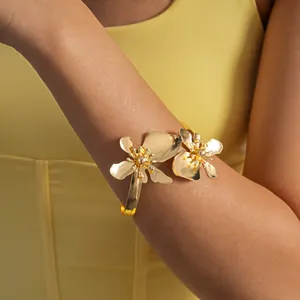 Detailweergave van de goudkleurige bovenarmband met bloemmotieven op het model.