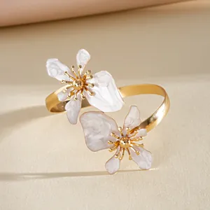 Gedetailleerd aanzicht van gouden armband met twee elegante parelwitte emaille bloemen