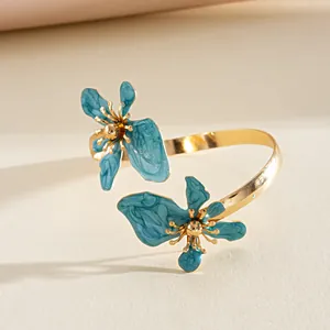 Detail van een gouden manchetarmband met prachtige blauwe emaille bloemen