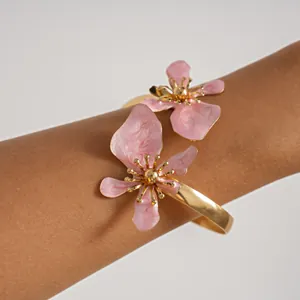 Detailopname van prachtige roze emaille bloesems op een gepolijste gouden metalen armmanchet