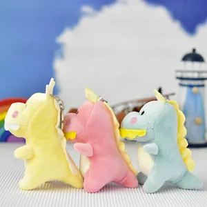 Dettaglio di tre portachiavi di dinosauro in peluche colorati in giallo, rosa e blu.