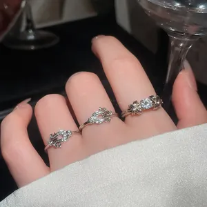 Dettaglio di tre lussuosi anelli in argento con cristalli scintillanti su una mano.