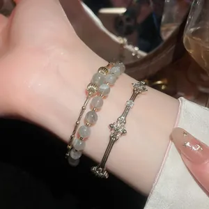 Dettaglio del bracciale con pietre di luna placcato oro e polsino a croce decorato.
